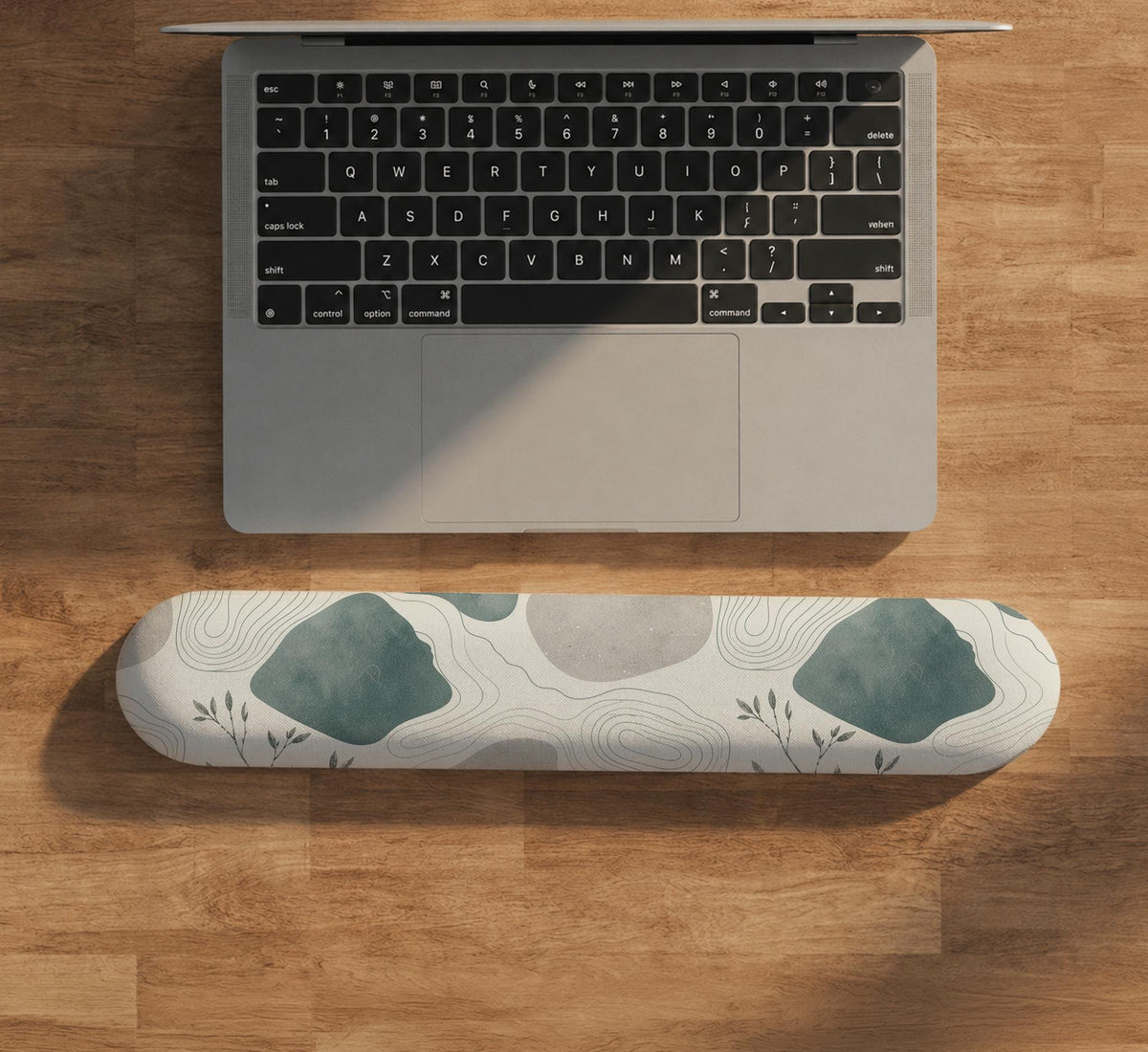 Sage green ergonomic mousepad and keyboard wrist rest with abstract shapes, soft gray details, cream space, topographic contour lines, and leafy branch accents.