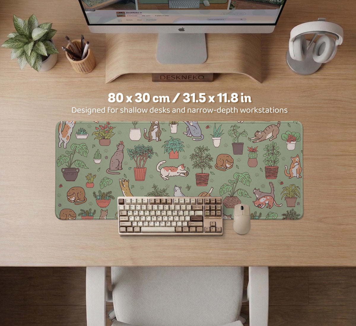 A desk mat with a repeating pattern of cats, leafy houseplants, cactus pots, and small plant-shop style details in sage green.