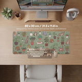 A desk mat with a repeating pattern of cats, leafy houseplants, cactus pots, and small plant-shop style details in sage green.