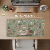 A desk mat with a repeating pattern of cats, leafy houseplants, cactus pots, and small plant-shop style details in sage green.