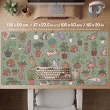 A desk mat with a repeating pattern of cats, leafy houseplants, cactus pots, and small plant-shop style details in sage green.