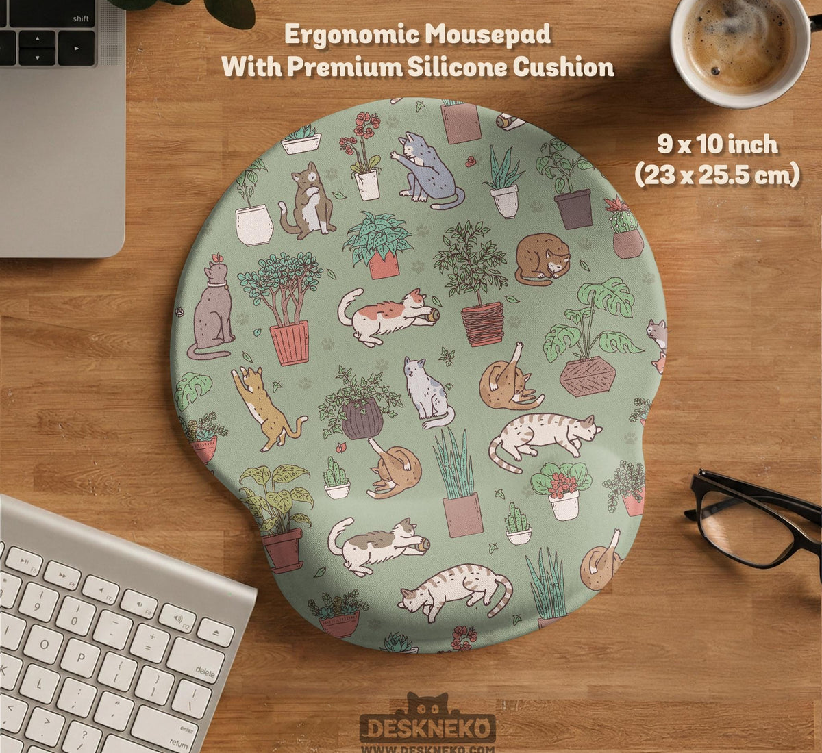A desk mat with a repeating pattern of cats, leafy houseplants, cactus pots, and small plant-shop style details in sage green.