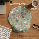A desk mat with a repeating pattern of cats, leafy houseplants, cactus pots, and small plant-shop style details in sage green.