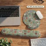A desk mat with a repeating pattern of cats, leafy houseplants, cactus pots, and small plant-shop style details in sage green.
