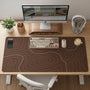 Brown desk mat with a repeating topographic contour line pattern in a neutral earth tone design.