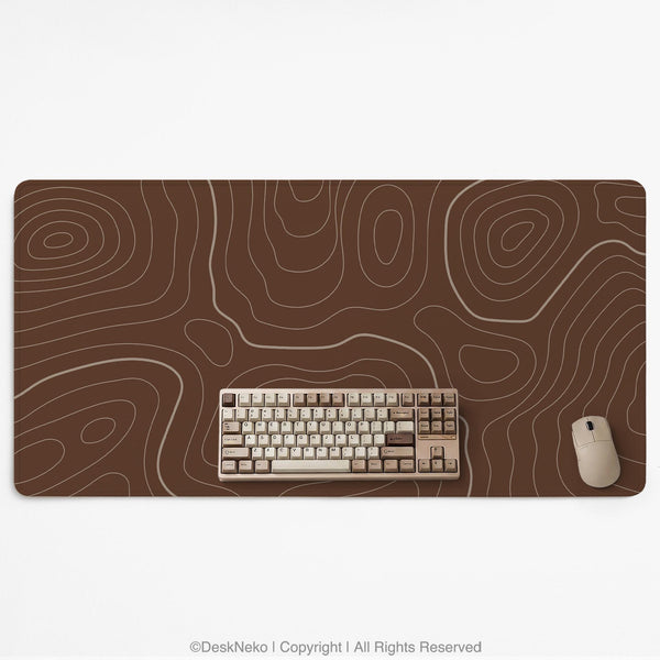Brown desk mat with a repeating topographic contour line pattern in a neutral earth tone design.