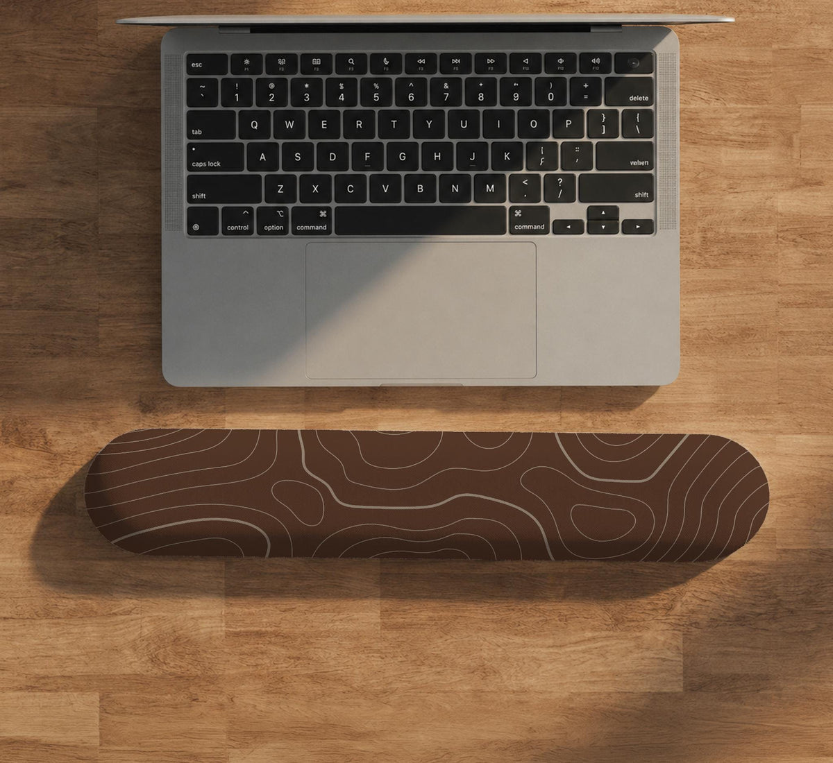 Brown mousepad and keyboard wrist rest with a topographic contour-line pattern.