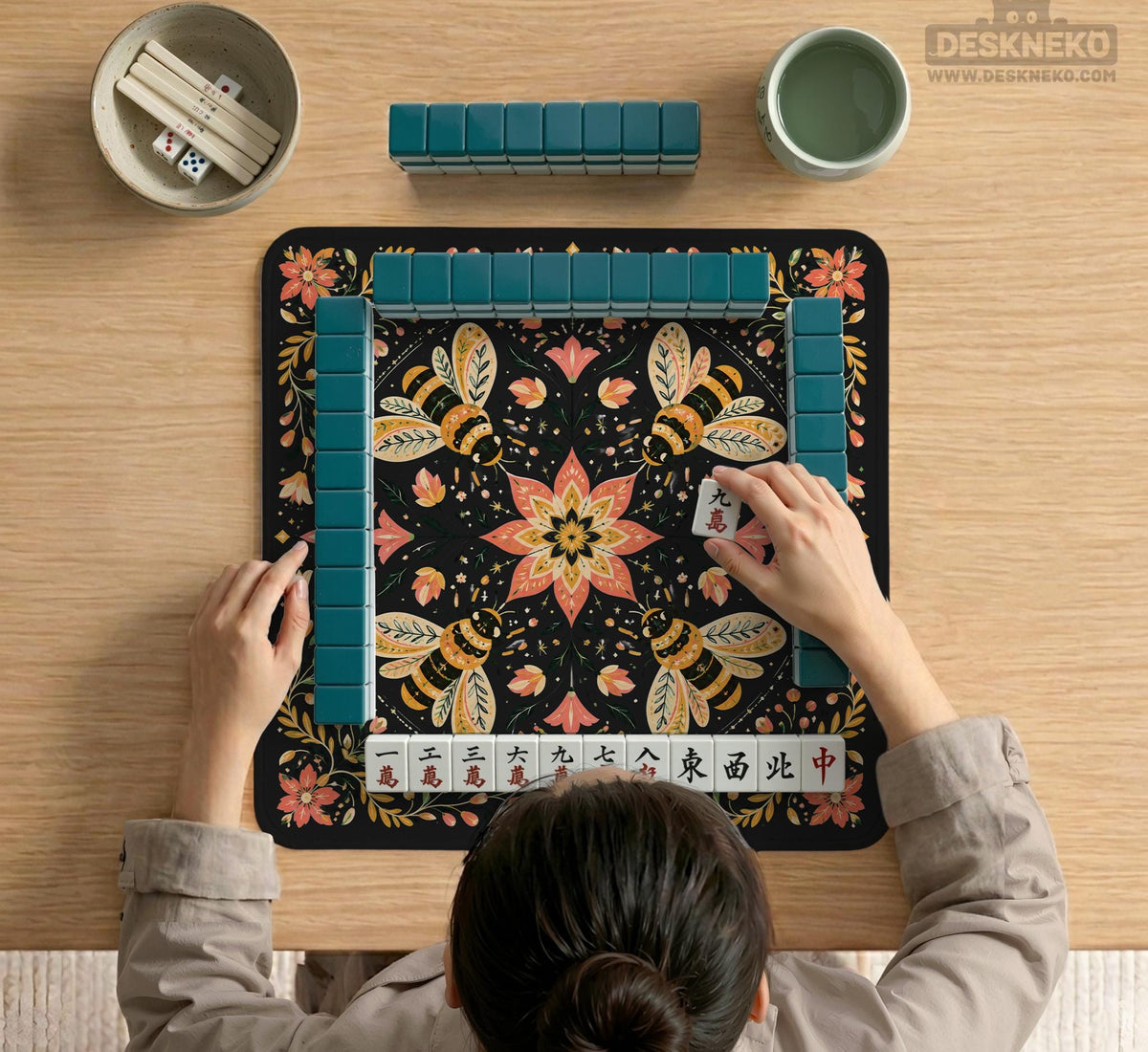 Black mahjong mat with a symmetrical botanical design, coral flowers, golden leaves, and small bees.