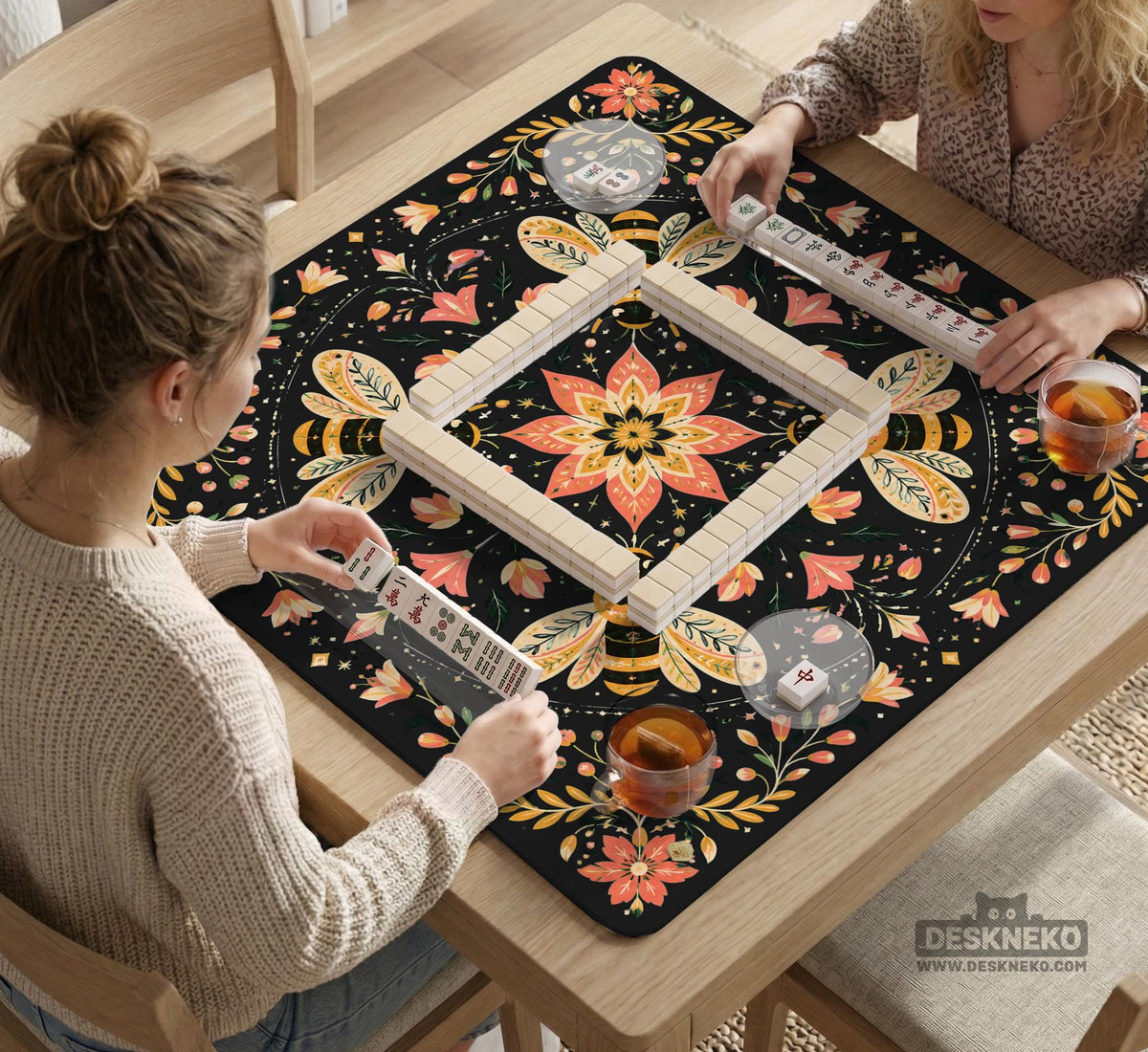 Black mahjong mat with a symmetrical botanical design, coral flowers, golden leaves, and small bees.