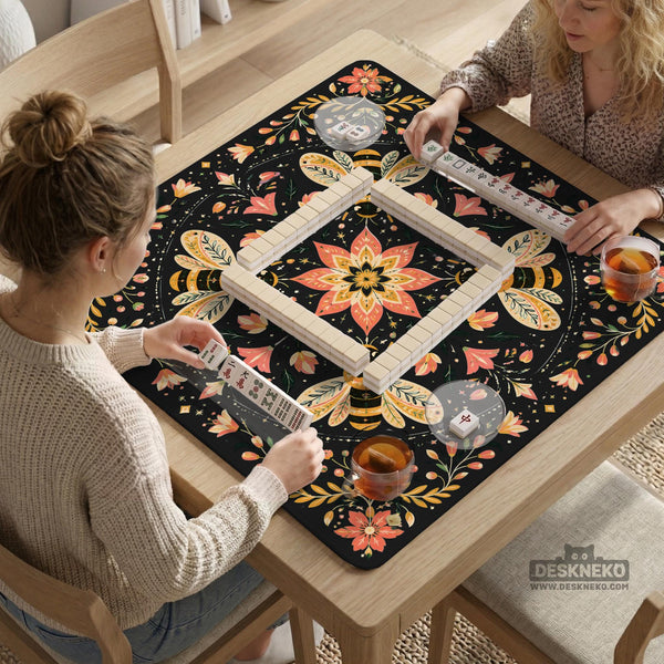 Black mahjong mat with a symmetrical botanical design, coral flowers, golden leaves, and small bees.