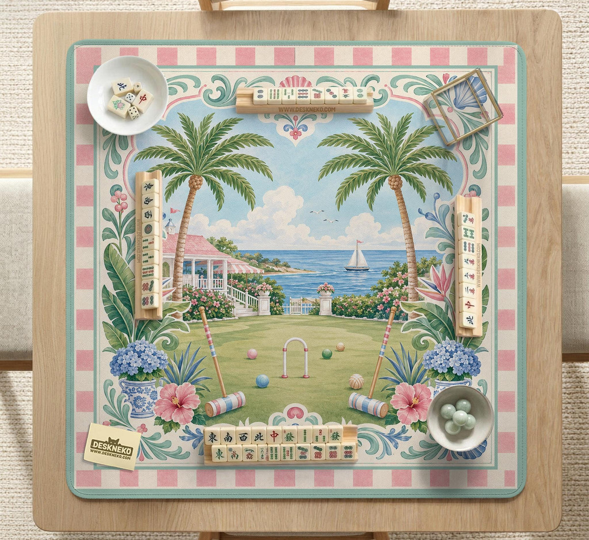 Pastel mahjong mat with a pink gingham border, seashells, hydrangea pots, palm trees, croquet details, and a coastal garden scene.