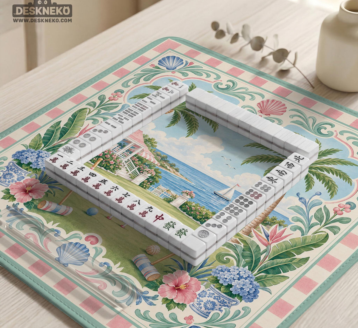 Pastel mahjong mat with a pink gingham border, seashells, hydrangea pots, palm trees, croquet details, and a coastal garden scene.