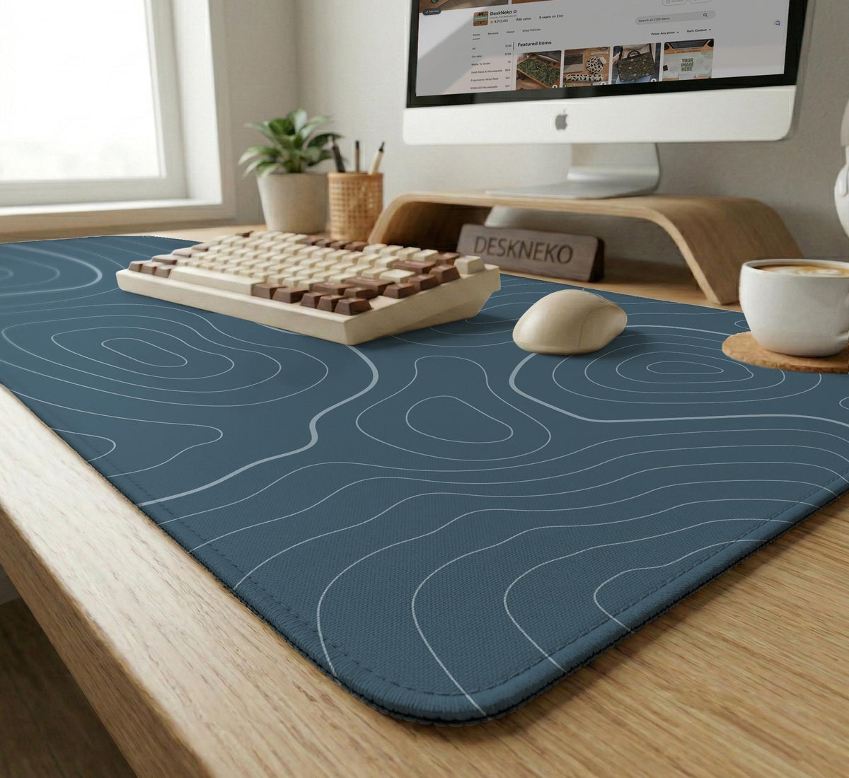 A slate blue desk mat with thin contour line map art on a light background.