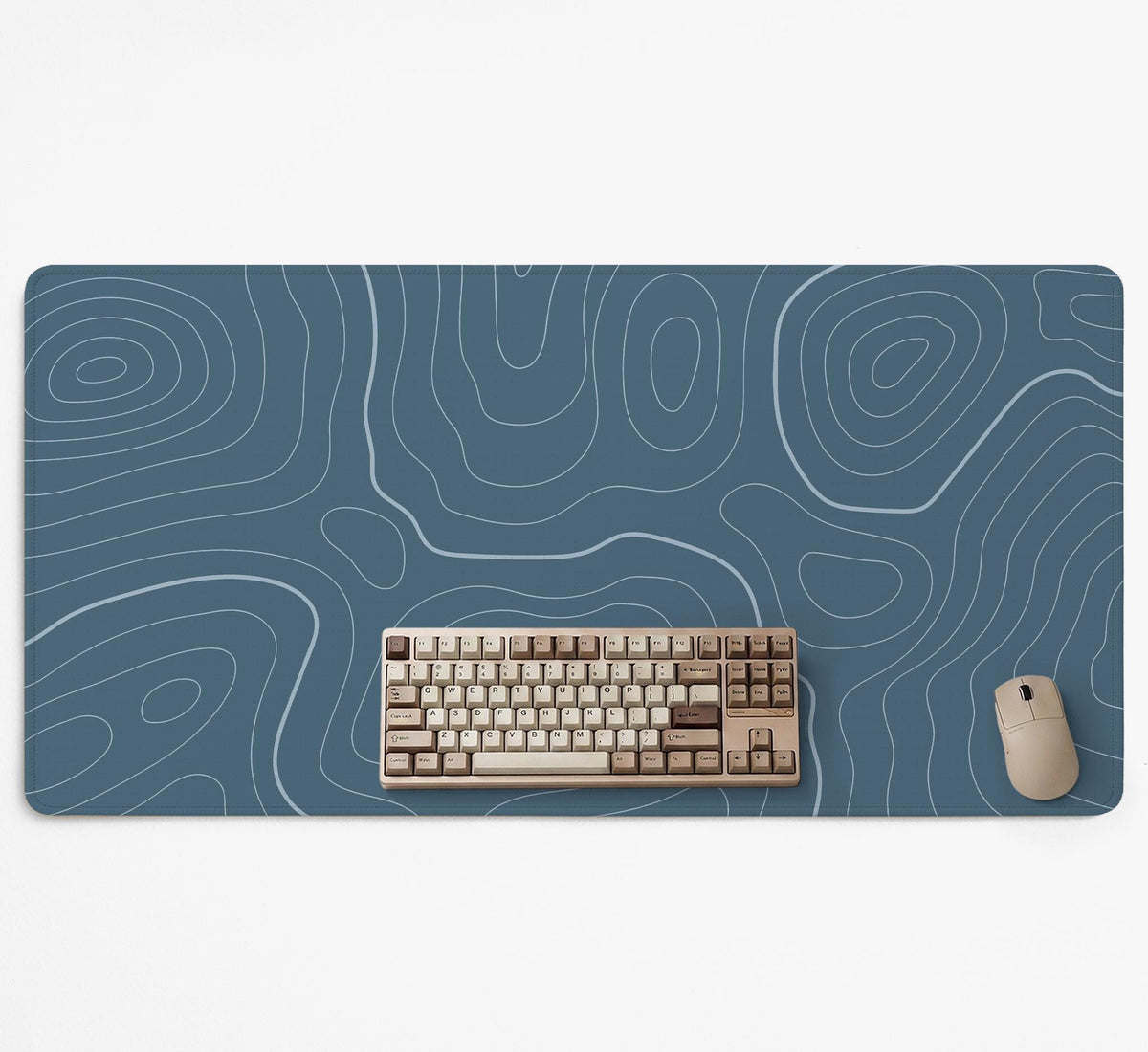 A slate blue desk mat with thin contour line map art on a light background.