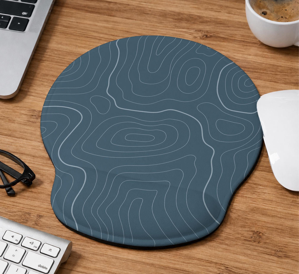 Muted blue desk mat with thin topographic line art pattern shown with matching mousepad and keyboard wrist rest options.