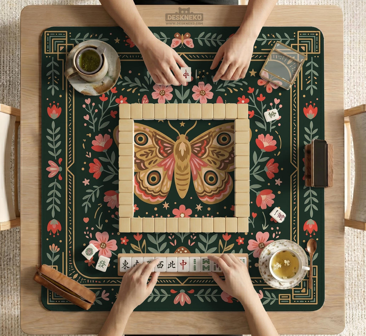 Dark green square mahjong mat with floral branches, small red blossoms, gold line details, and a large moth in the center.