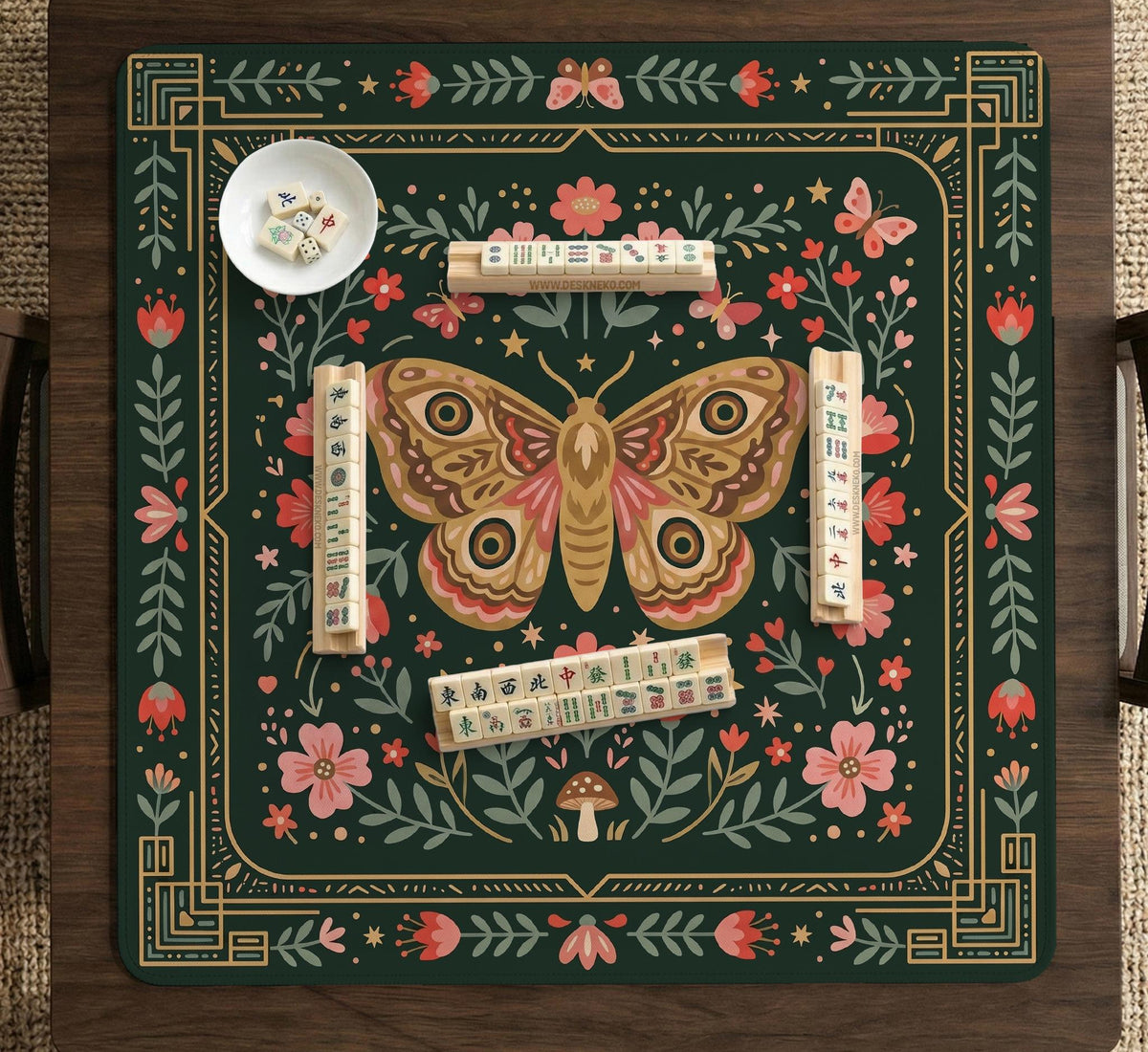 Dark green square mahjong mat with floral branches, small red blossoms, gold line details, and a large moth in the center.
