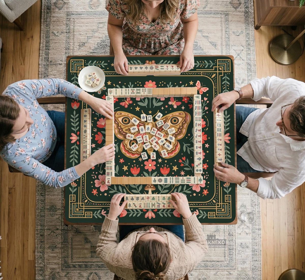 Dark green square mahjong mat with floral branches, small red blossoms, gold line details, and a large moth in the center.