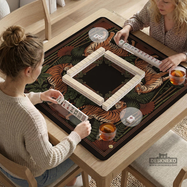 Black square mahjong mat with mirrored tiger faces, bamboo, dark tropical leaves, ornate border details, and orange accents.