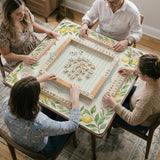 Square yellow mahjong mat with a citrus garden border, green vines, pink blossoms, aqua accents, and a plain center play area.