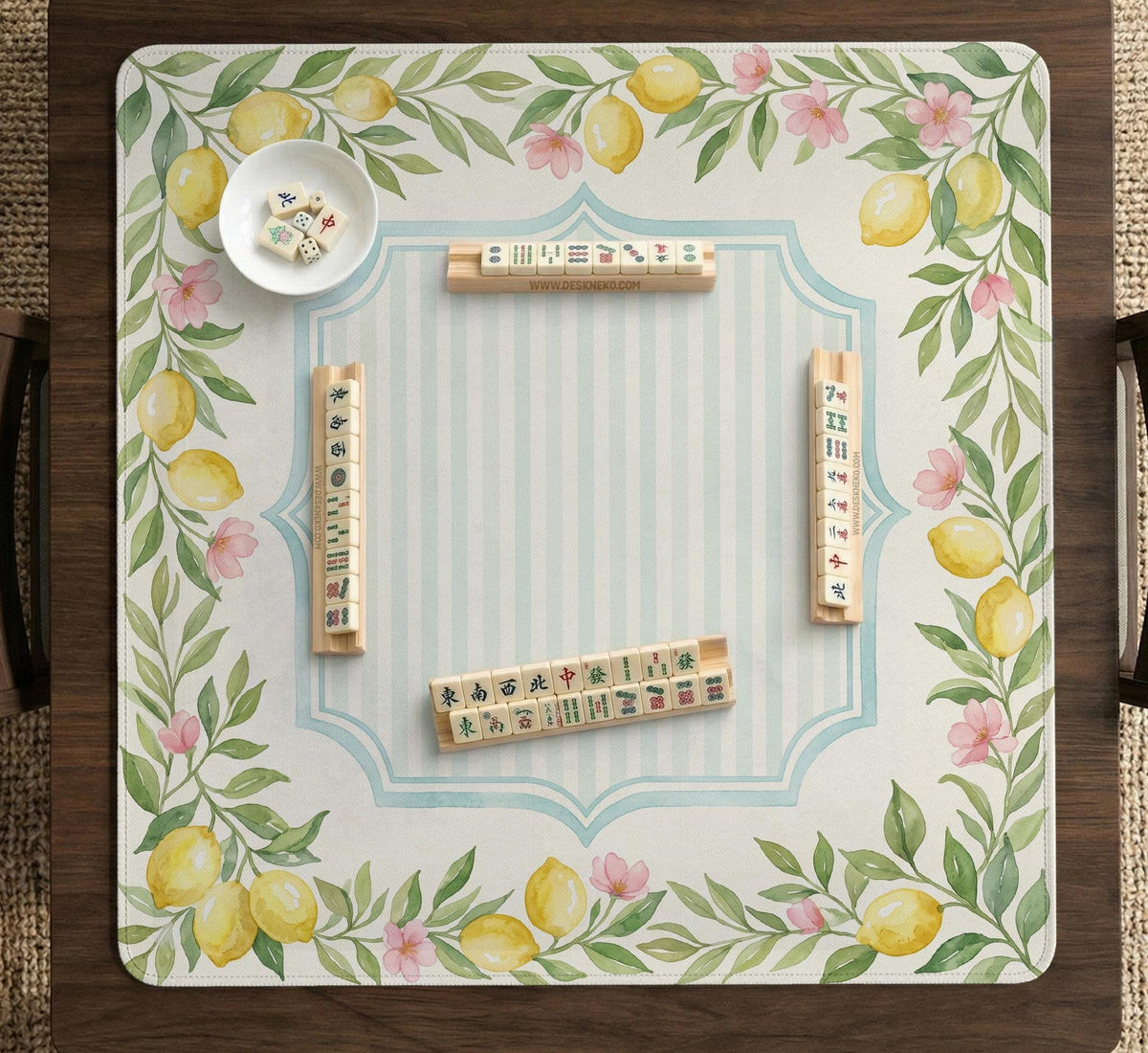 Square yellow mahjong mat with a citrus garden border, green vines, pink blossoms, aqua accents, and a plain center play area.