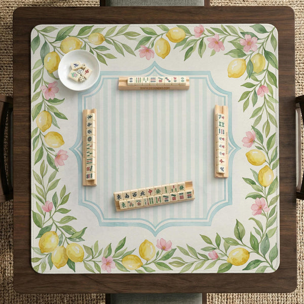 Square yellow mahjong mat with a citrus garden border, green vines, pink blossoms, aqua accents, and a plain center play area.