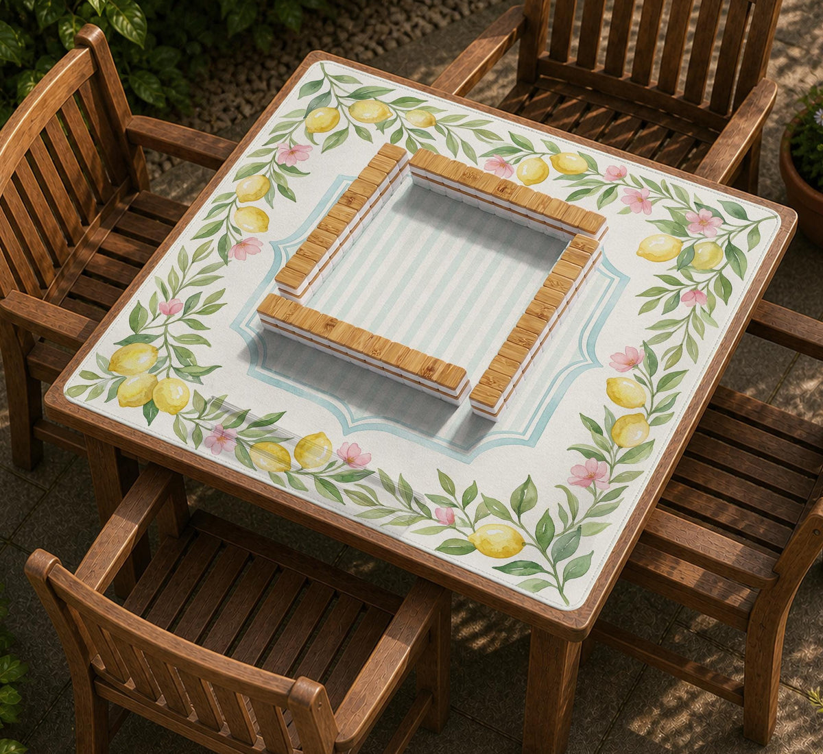 Square yellow mahjong mat with a citrus garden border, green vines, pink blossoms, aqua accents, and a plain center play area.