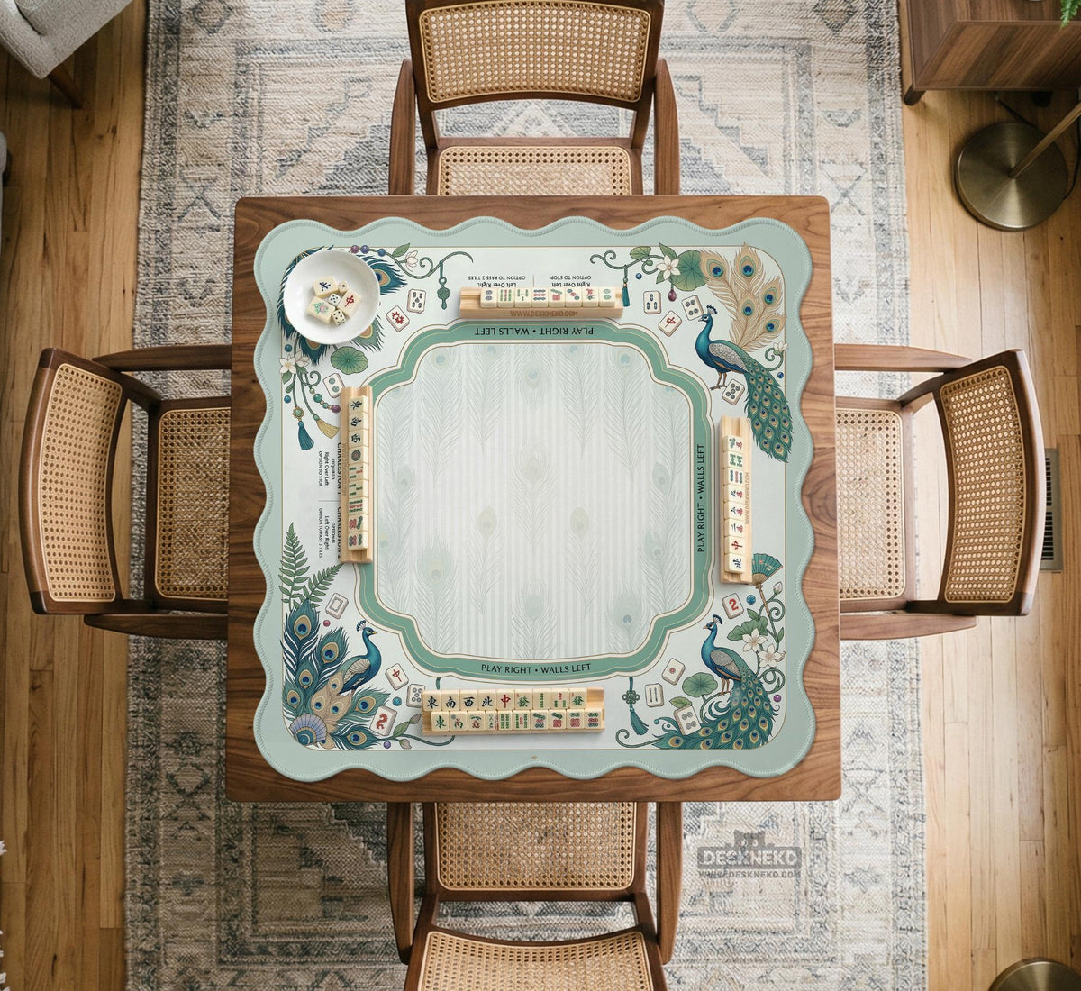 Teal square mahjong mat with peacock feathers, soft floral pattern, tassel details, and printed rule guide text in the center.