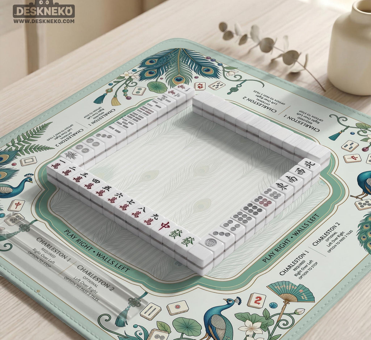 Teal square mahjong mat with peacock feathers, soft floral pattern, tassel details, and printed rule guide text in the center.