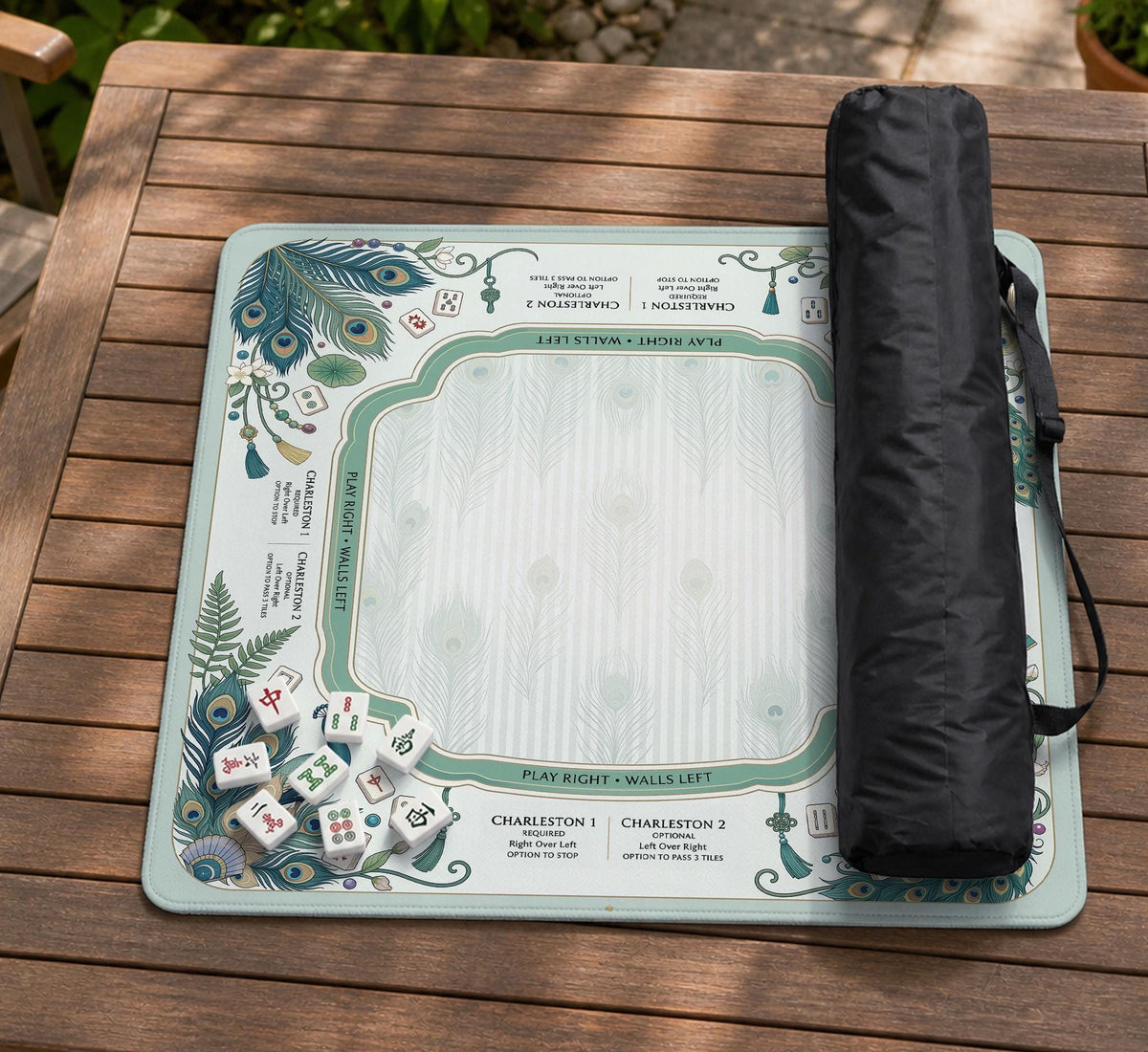 Teal square mahjong mat with peacock feathers, soft floral pattern, tassel details, and printed rule guide text in the center.