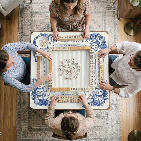 Blue and white square mahjong mat with lucky cat artwork, floral chinoiserie pattern, tile icons, and a rule guide layout.
