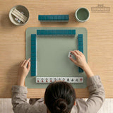 A plain light sage green square mahjong mat with a smooth solid-color surface.