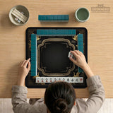 Black and gold square mahjong mat with an art deco crane and floral border, rule reminders around the edges, and a blank center area.