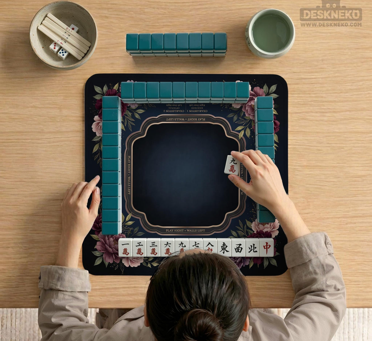 Burgundy mahjong mat with a floral border, gold botanical details, and printed American Mahjong rules on a dark background.