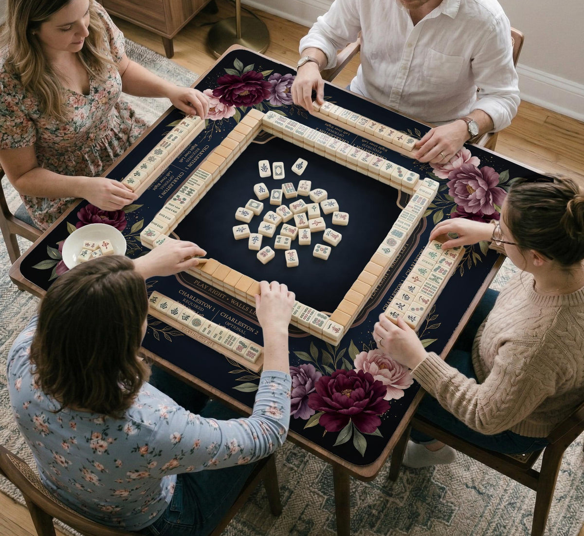 Burgundy mahjong mat with a floral border, gold botanical details, and printed American Mahjong rules on a dark background.