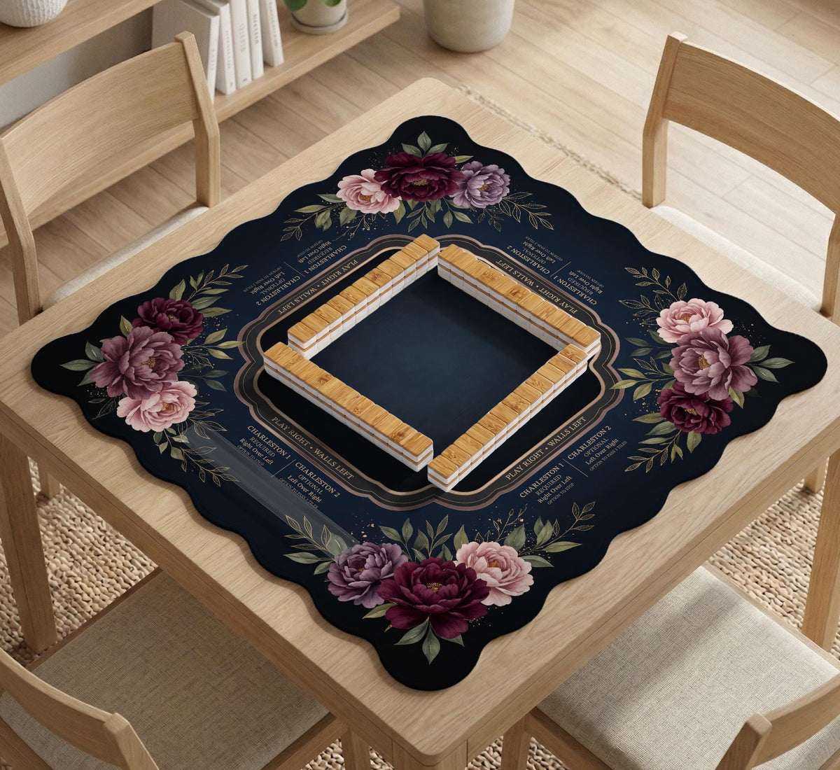 Burgundy mahjong mat with a floral border, gold botanical details, and printed American Mahjong rules on a dark background.