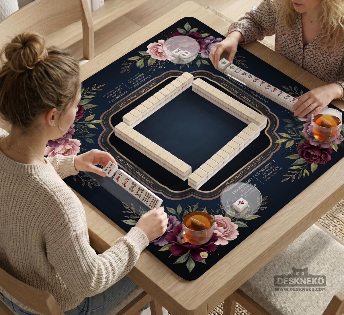 Burgundy mahjong mat with a floral border, gold botanical details, and printed American Mahjong rules on a dark background.