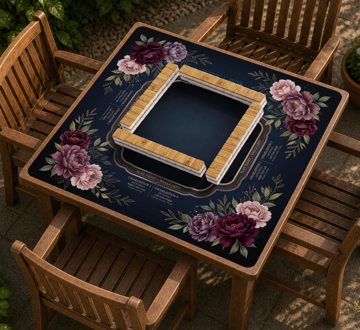 Burgundy mahjong mat with a floral border, gold botanical details, and printed American Mahjong rules on a dark background.