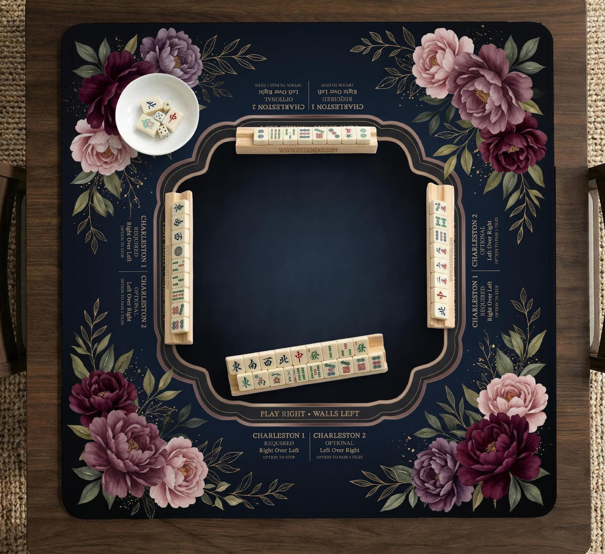 Burgundy mahjong mat with a floral border, gold botanical details, and printed American Mahjong rules on a dark background.