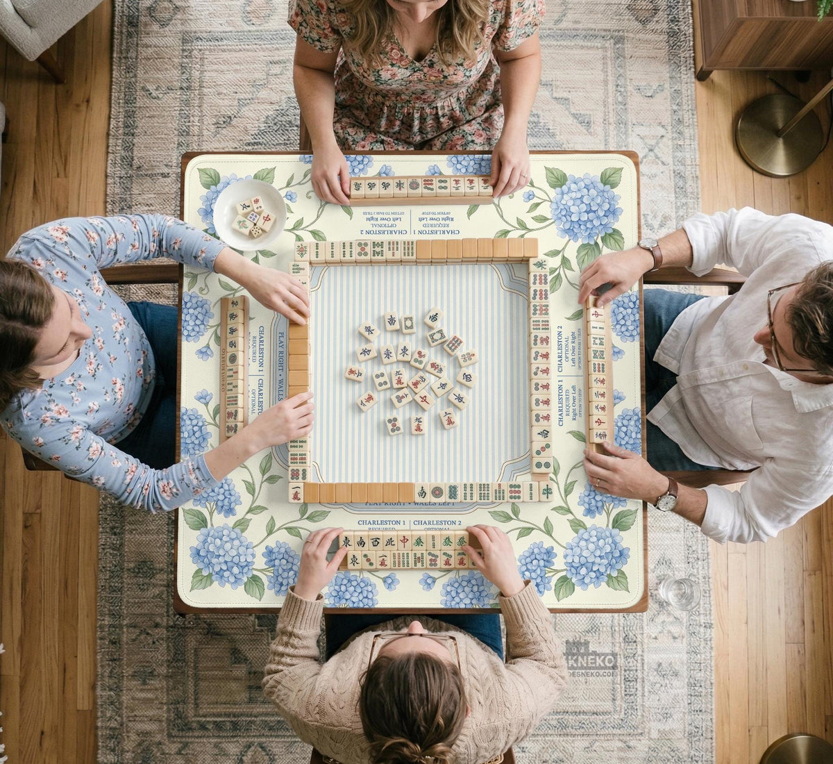 A square mahjong mat with blue hydrangea flowers, green vines, a cream background, a striped center, and printed rules around the border.