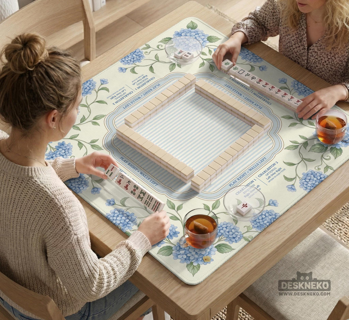 A square mahjong mat with blue hydrangea flowers, green vines, a cream background, a striped center, and printed rules around the border.