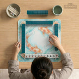 Pastel aqua square mahjong mat with orange koi fish, lotus flowers, lily pads, and flowing water lines.