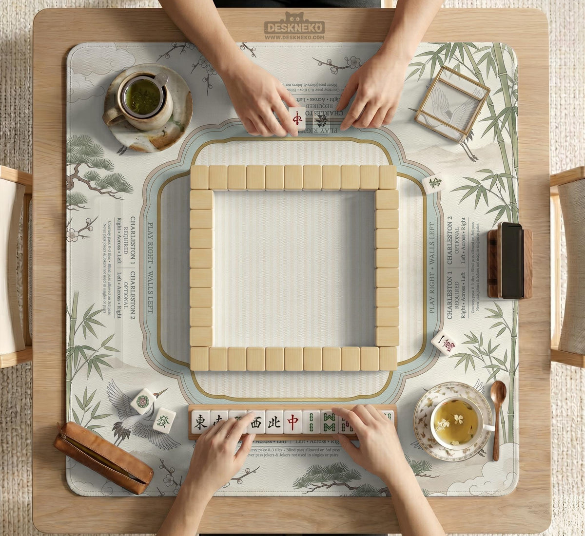Sage green scalloped mahjong mat with bamboo, crane, and blossom illustration and printed rules around the border.