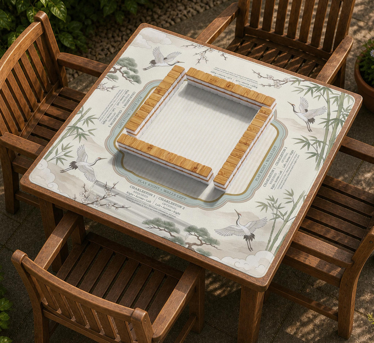 Sage green scalloped mahjong mat with bamboo, crane, and blossom illustration and printed rules around the border.