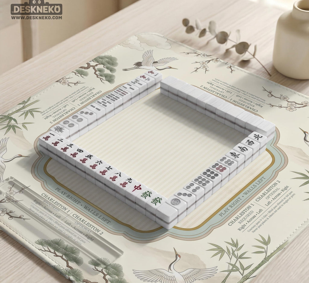 Sage green scalloped mahjong mat with bamboo, crane, and blossom illustration and printed rules around the border.