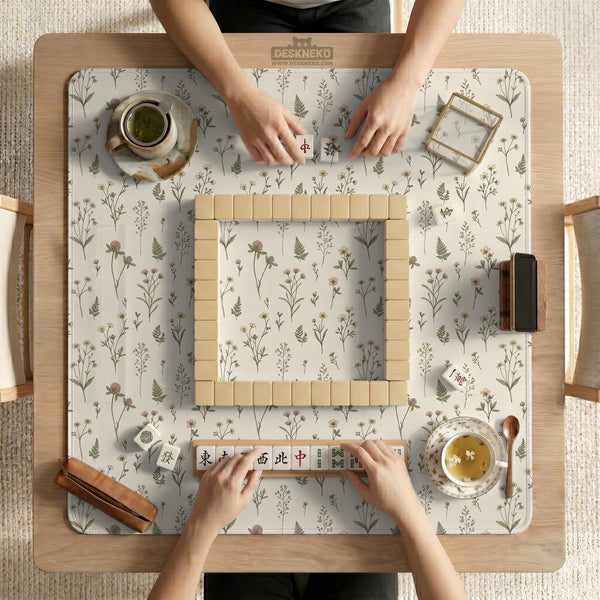Cream mahjong mat with a floral pattern of small wildflowers and sage leaves, shown with a scalloped edge on a light neutral background.