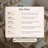 Beige mahjong mat with a botanical floral bird design, blush flowers, olive green leaves, black flower accents, and a warm linen-style background. Scalloped edge option shown.