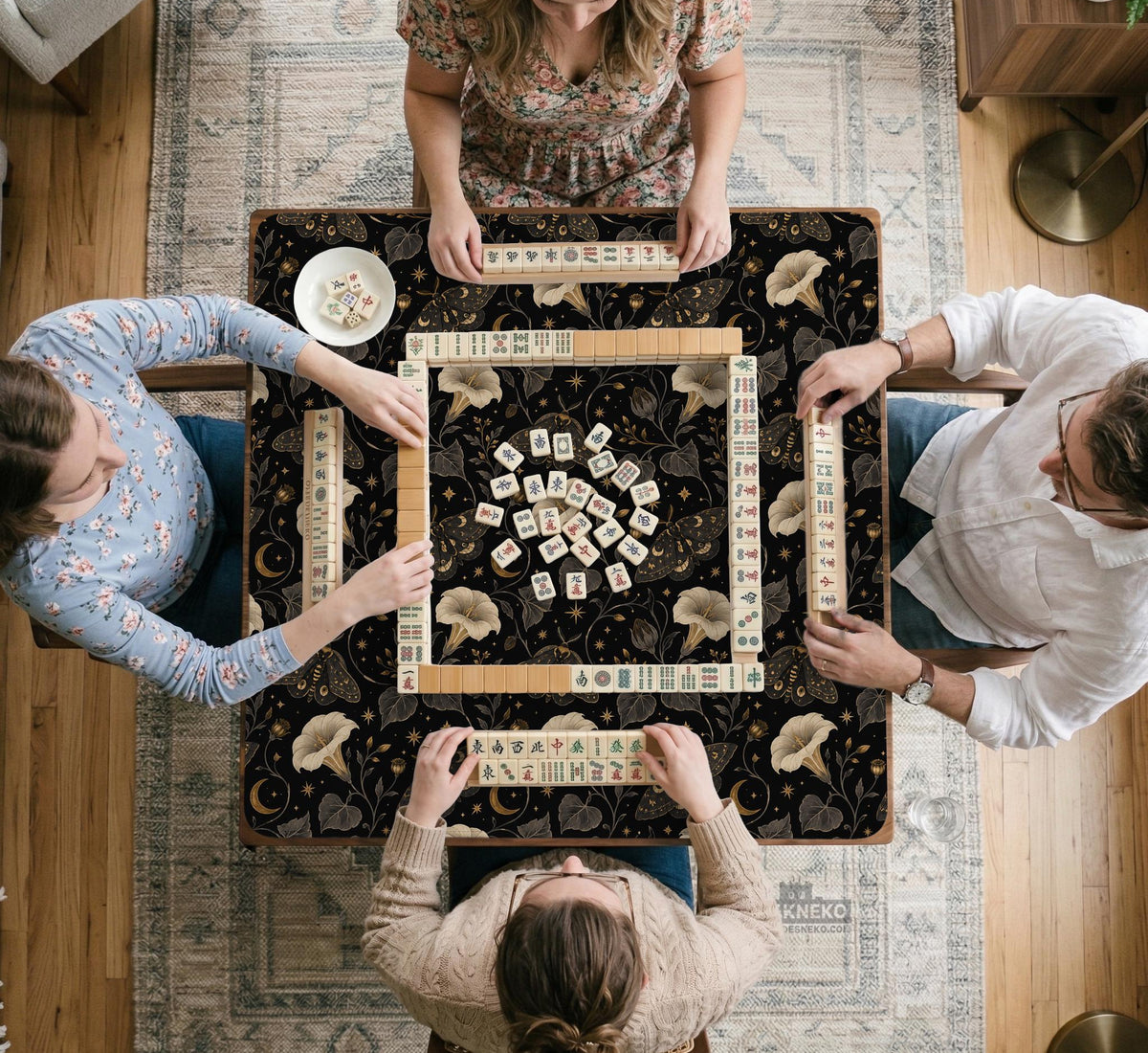 Black square mahjong mat with moths, moonflowers, crescent moons, and scattered stars in a celestial floral pattern.