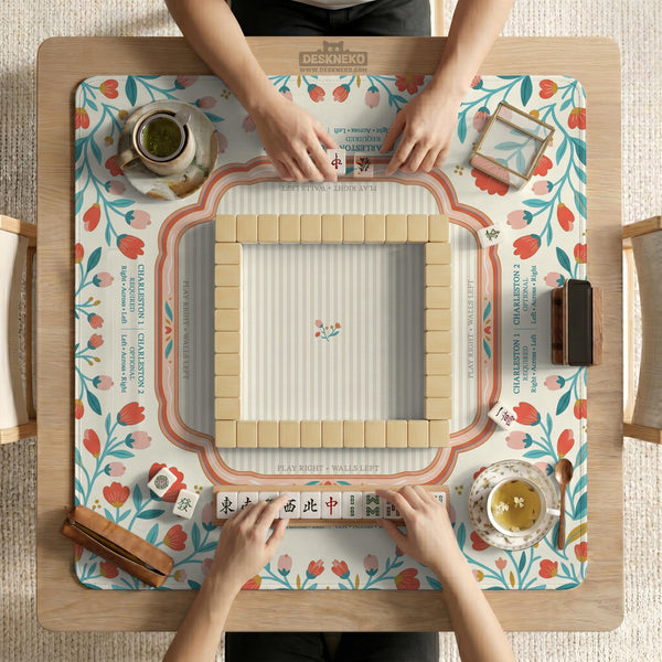 Cream mahjong mat with a coral and teal floral border, rule layout text, Charleston guide notes, and a blank center area for tile play.