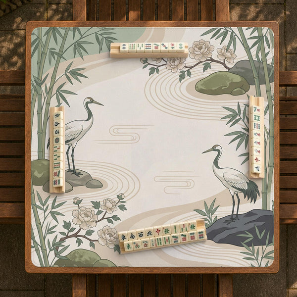 Square mahjong mat with a cream background, sage green cranes, bamboo leaves, peony branches, stones, and thin linework.
